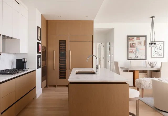 a kitchen with stainless steel appliances granite countertop a sink a stove a refrigerator a dining table and chairs with wooden floor