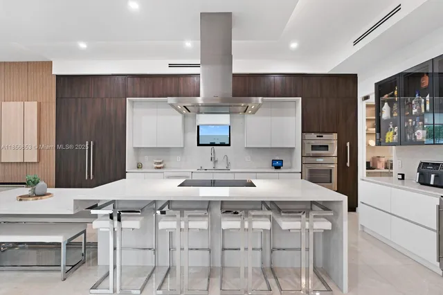 a kitchen with stainless steel appliances kitchen island granite countertop a table chairs and a refrigerator