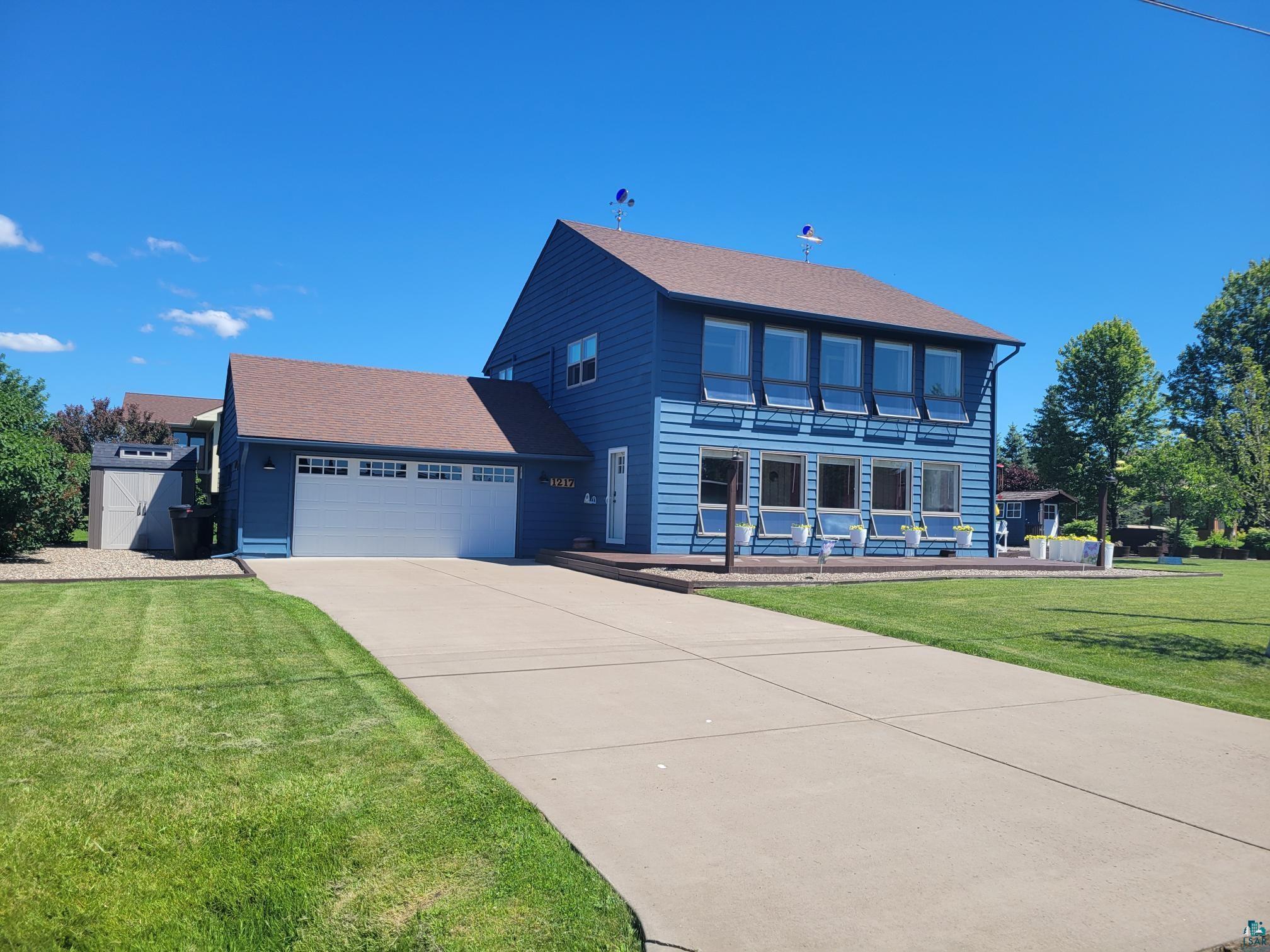 View of front facade featuring a garage and a front lawn