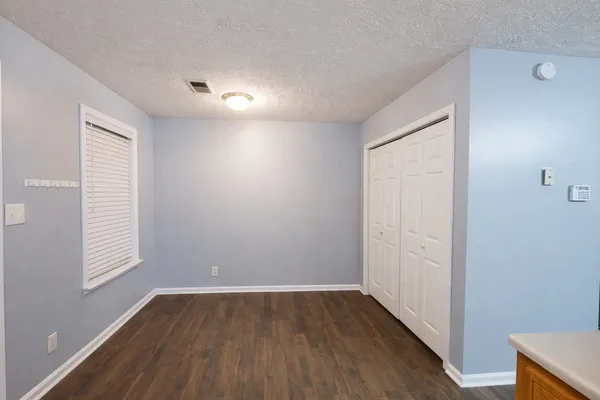 an empty room with wooden floor and windows