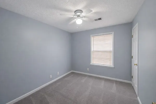 an empty room with a window and a ceiling fan