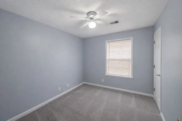 an empty room with a window and a ceiling fan