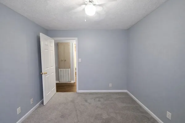 an empty room with a chandelier fan and windows