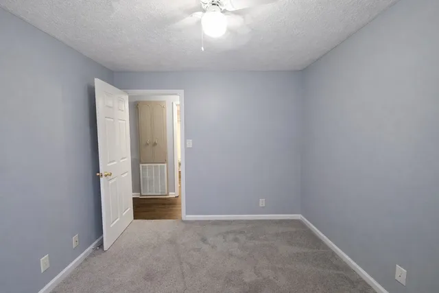 an empty room with a chandelier fan and windows