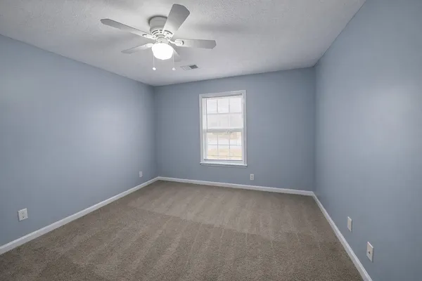 an empty room with a window and a fan