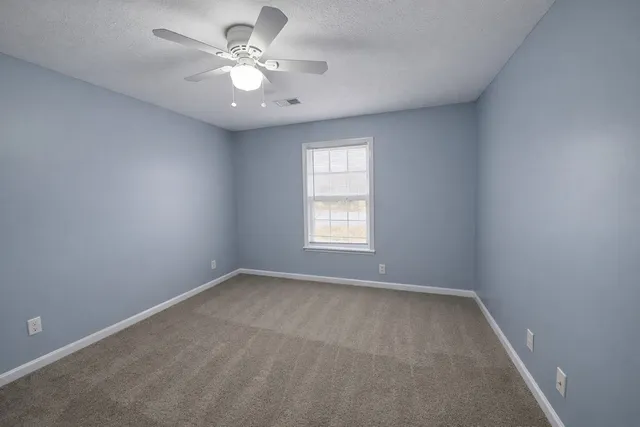 an empty room with a window and a fan