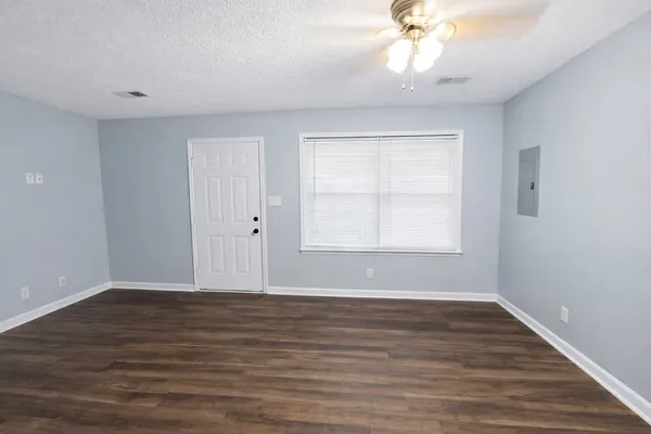 a view of an empty room with wooden floor and a window