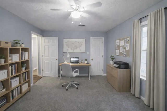 a view of a workspace with furniture and a window