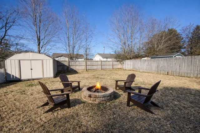 a view of a backyard with chairs and a fire pit