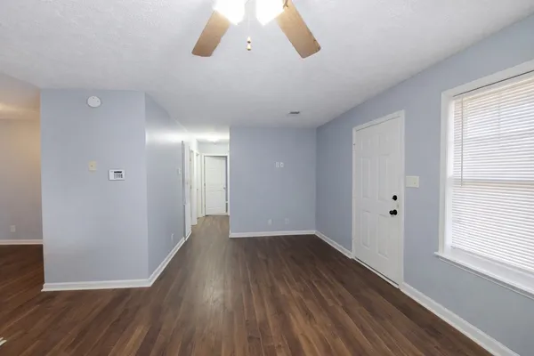 a view of an empty room with wooden floor and a window