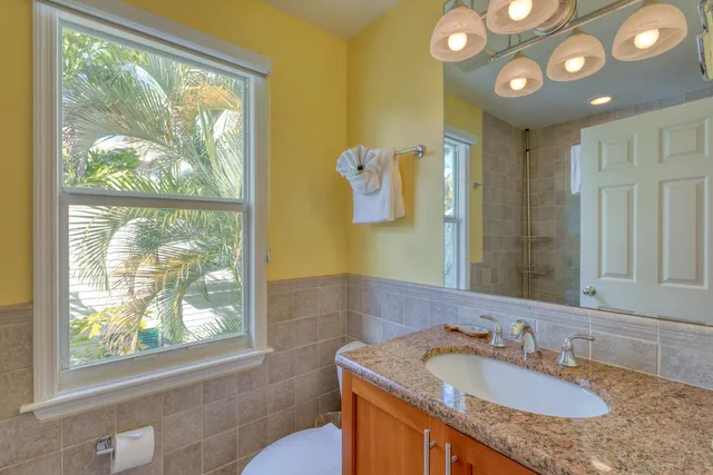 a bathroom with a granite countertop sink and a large mirror next to a window