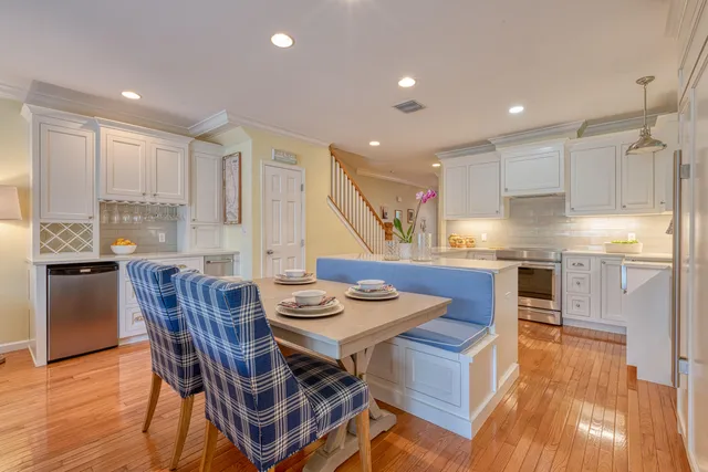a kitchen with stainless steel appliances kitchen island granite countertop a table chairs sink and cabinets