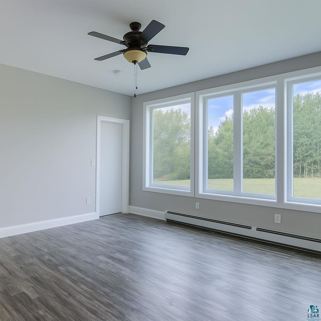 6030 Mitchell Road Iron River, WI 54847 - Photo 17 of 45 Spare room featuring dark wood-style floors, baseboard heating, and ceiling fan