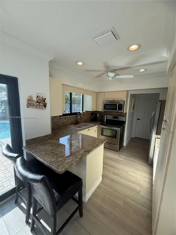 a large kitchen with stainless steel appliances granite countertop a lot of counter space and wooden floor
