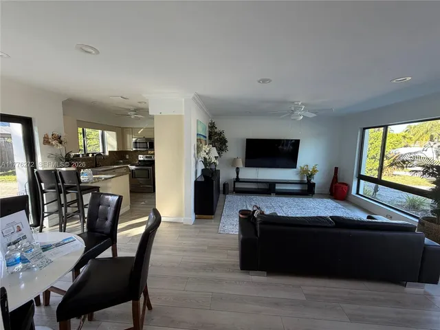 a living room with stainless steel appliances furniture and a flat screen tv