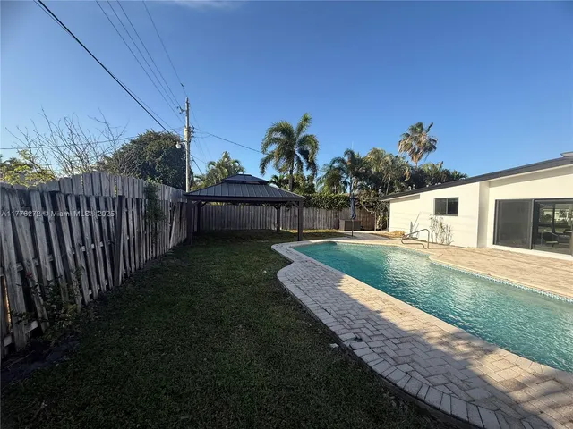 a view of a backyard with couches under an umbrella
