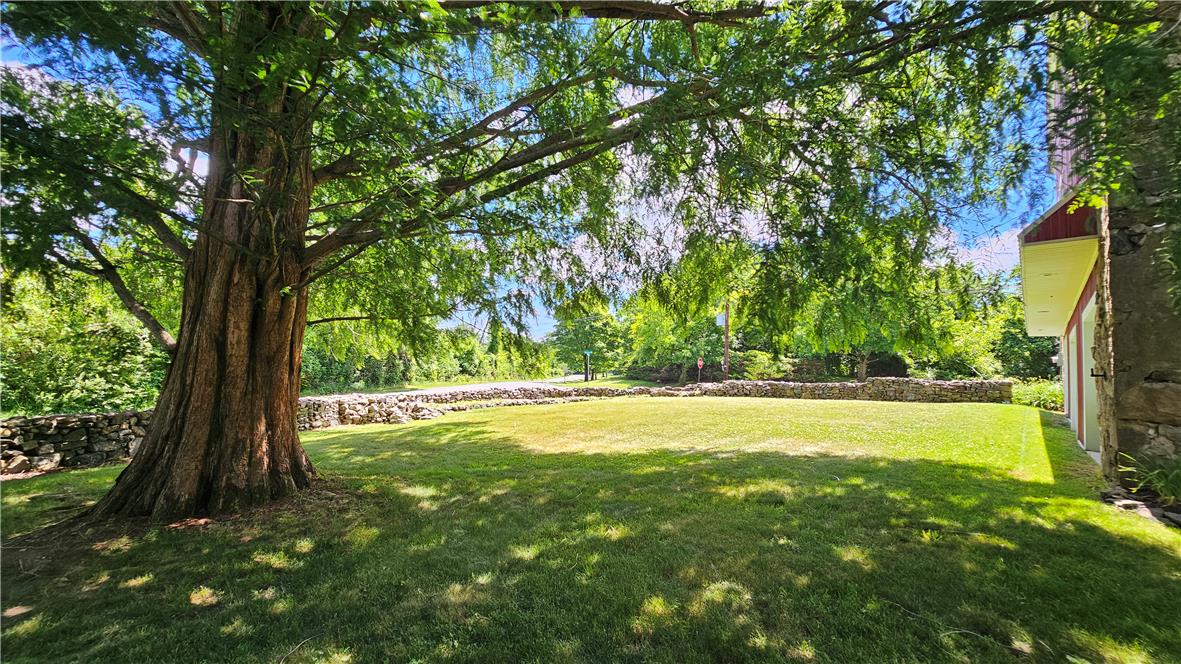 585 Buttermilk Road Hellertown, PA 18055 - Photo 62 of 82 A spacious lawn offers verdant tranquility beside a stone-faced home, framed by a venerable tree and historic stone walls.
