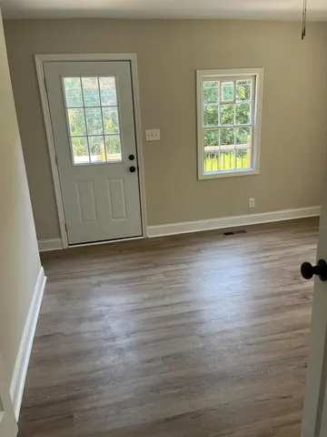 an empty room with wooden floor and windows