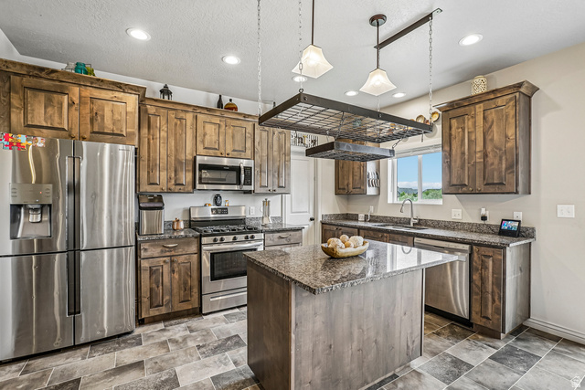 203 North 1900th Street West Mapleton, UT 84664 - Photo 8 of 48 Kitchen featuring an island with a stone-finish countertop, stainless steel appliances, wood-finish cabinetry, recessed ceiling lights, and tiled flooring