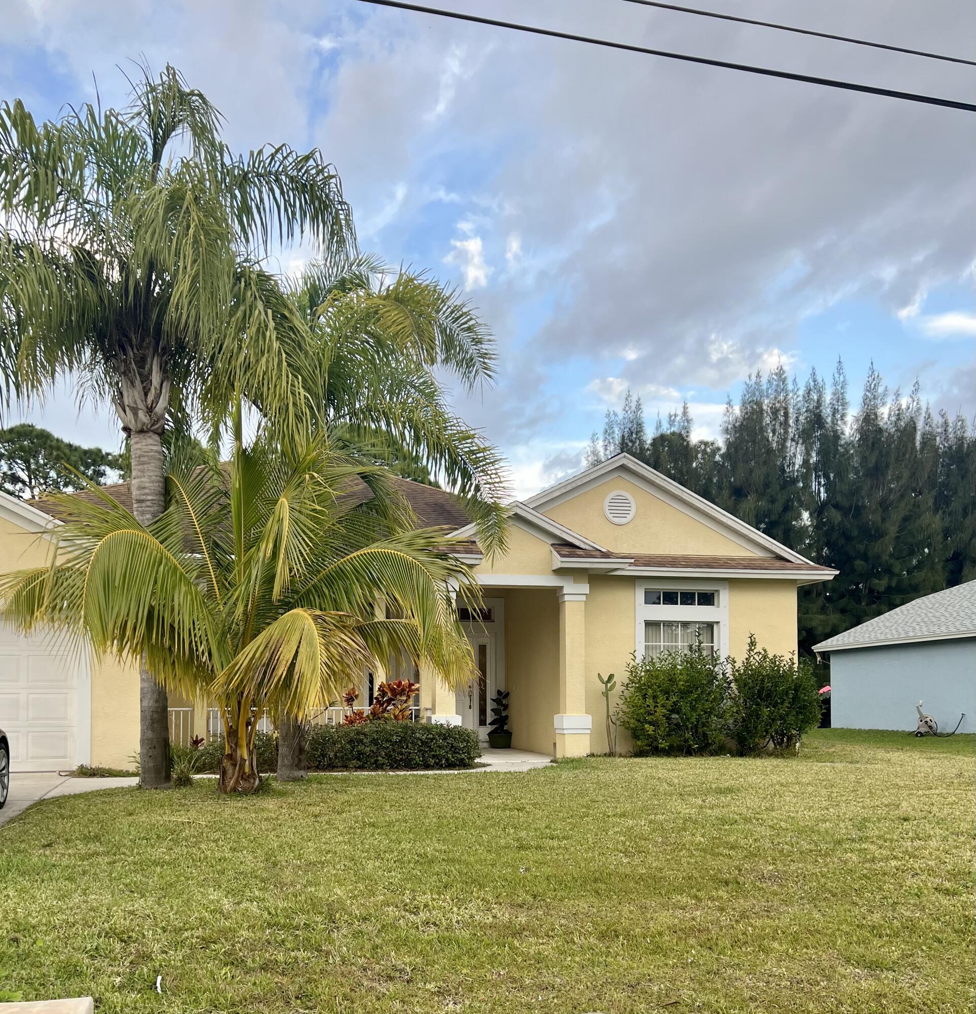 a front view of a house with a yard and palm trees