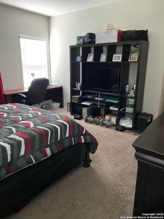 a bedroom with a bed a flat screen tv and windows