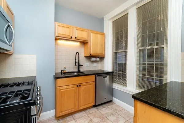 a kitchen with granite countertop a sink stove and refrigerator