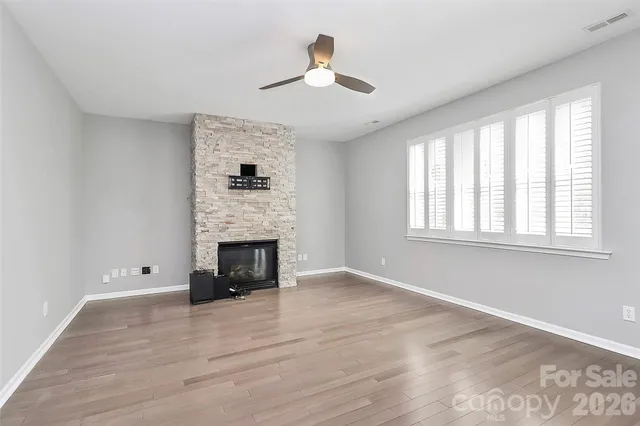 an empty room with windows fireplace and wooden floor