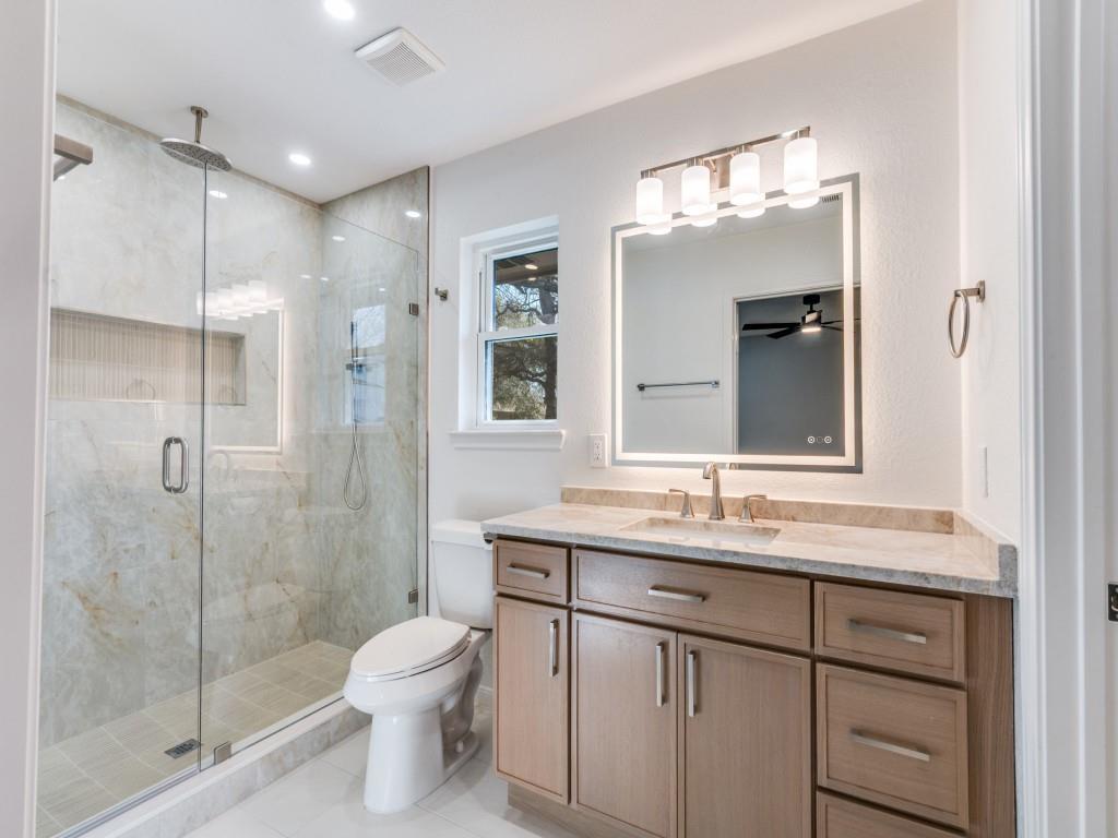 205 Laurel Street Mansfield, TX 76063 - Photo 9 of 24 a bathroom with a granite countertop sink toilet a large mirror a shower and vanity