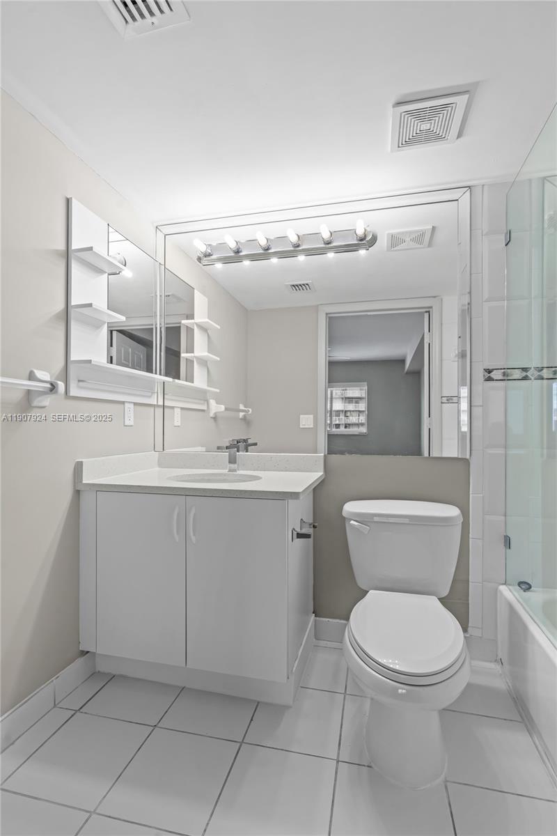 2475 Northwest 16th St Road, Unit 616 Miami, FL 33125 - Photo 24 of 32 a bathroom with a toilet a sink and mirror