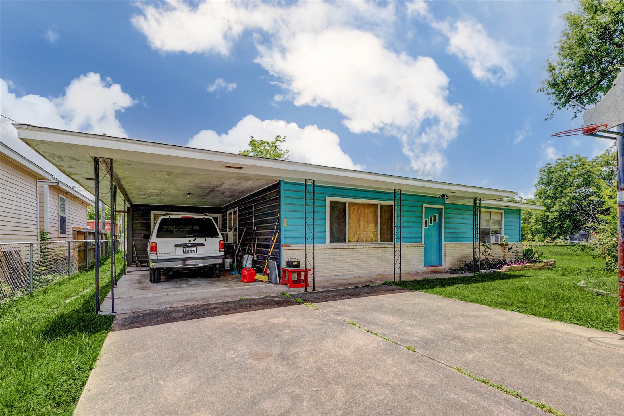 8537 Rannie Road Houston, TX 77080 - Photo 14 of 15 Front drive view showing existing concrete parking and covered vehicle access on the property. While the structure is secondary and sold as-is, this image helps demonstrate the lot’s practical utility, existing approach, and potential parking function. The wide driveway, open frontage, and surrounding yard space support the property’s appeal for buyers seeking land, access, storage, or future-use flexibility.