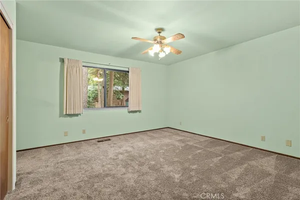 an empty room with windows and fan