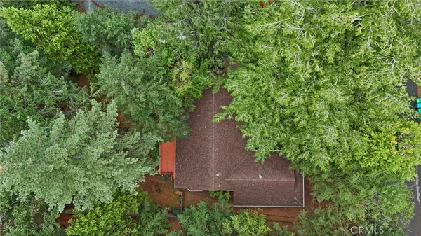 an aerial view of a house with outdoor space and trees all around