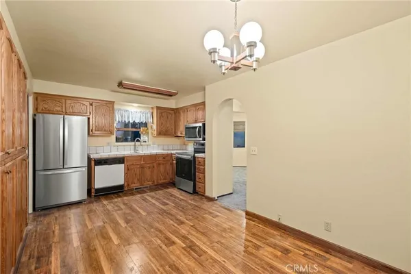 a kitchen with stainless steel appliances granite countertop a refrigerator a sink dishwasher a stove and a dining table with wooden floor