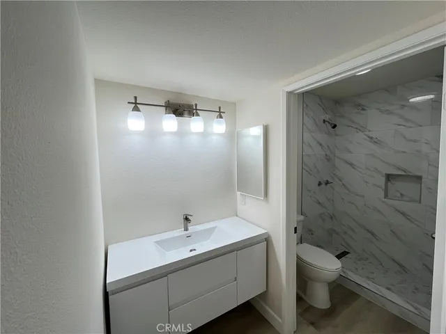a bathroom with a granite countertop sink a toilet and shower