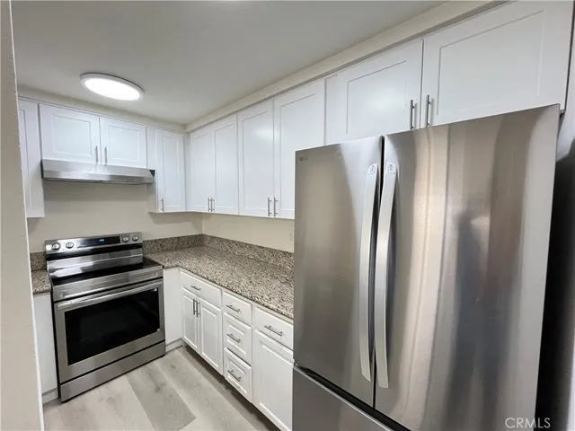 a kitchen with stainless steel appliances granite countertop a refrigerator and a stove top oven