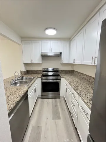 a kitchen with granite countertop a sink stove and cabinets
