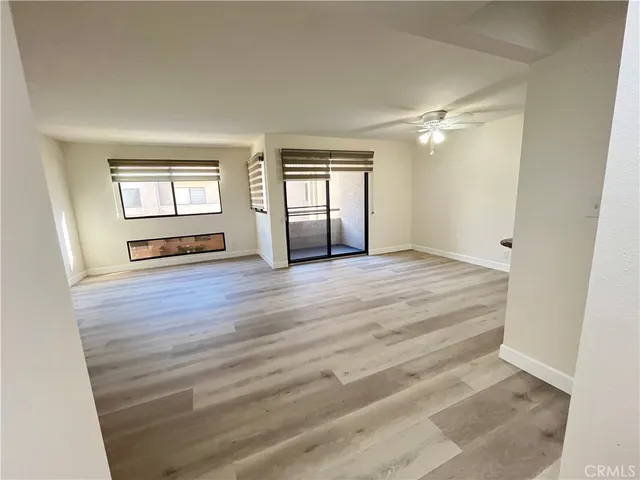 a view of an empty room with a window and wooden floor