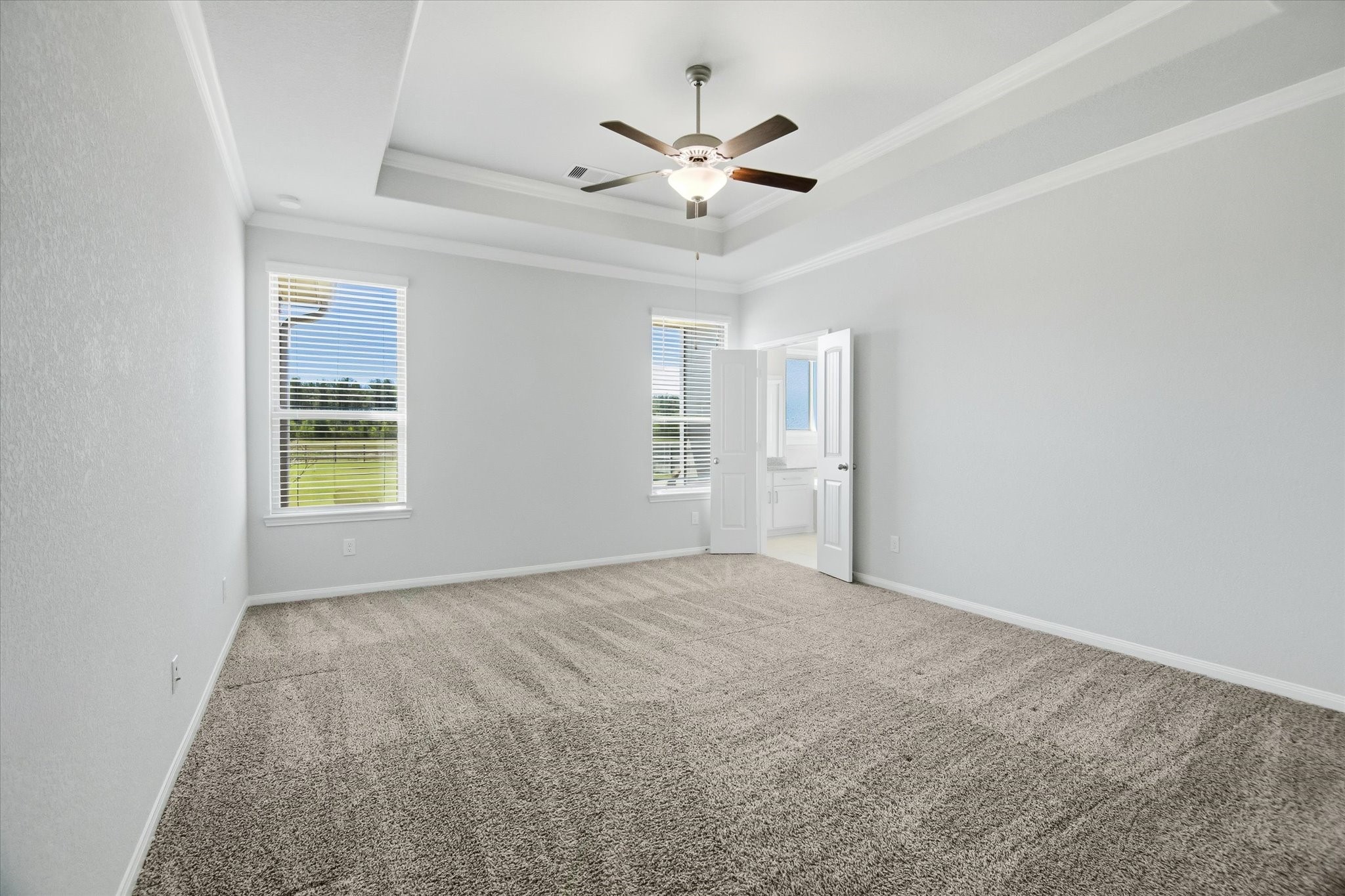 16738 Rockwall Street Conroe, TX 77303 - Photo 15 of 42 The primary bedroom is a peaceful retreat designed for rest and relaxation. A tray ceiling adds architectural interest and is complemented by a ceiling fan for comfort year-round. Windows overlook the backyard, bringing in soft natural light and calming views.