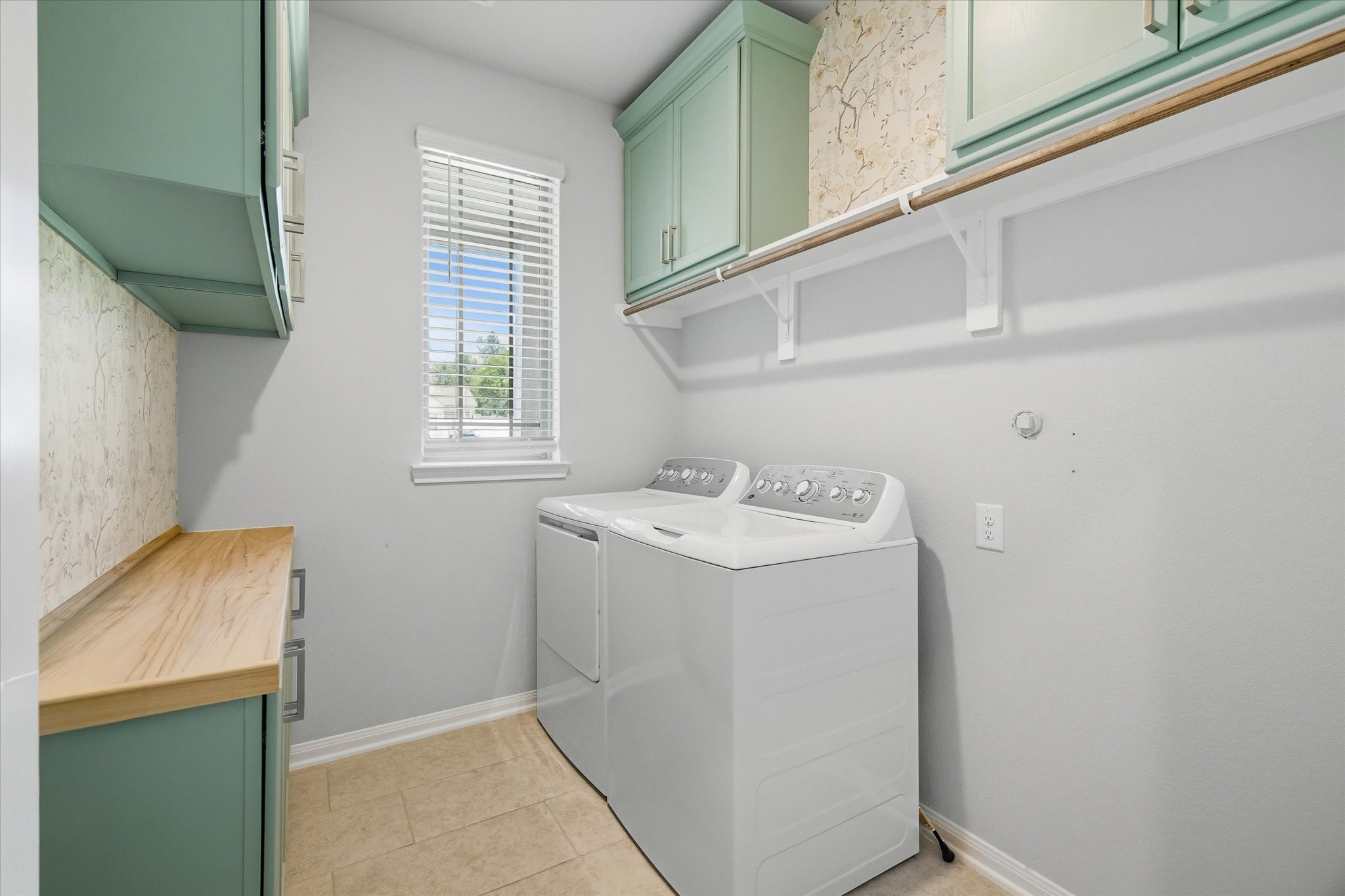 16738 Rockwall Street Conroe, TX 77303 - Photo 29 of 42 The utility room goes beyond the basics, offering a well-equipped space with a washer and dryer, cabinetry, shelving, a hanging rod, and a countertop for easy organization. A window invites in natural light, giving the room an open, efficient feel.