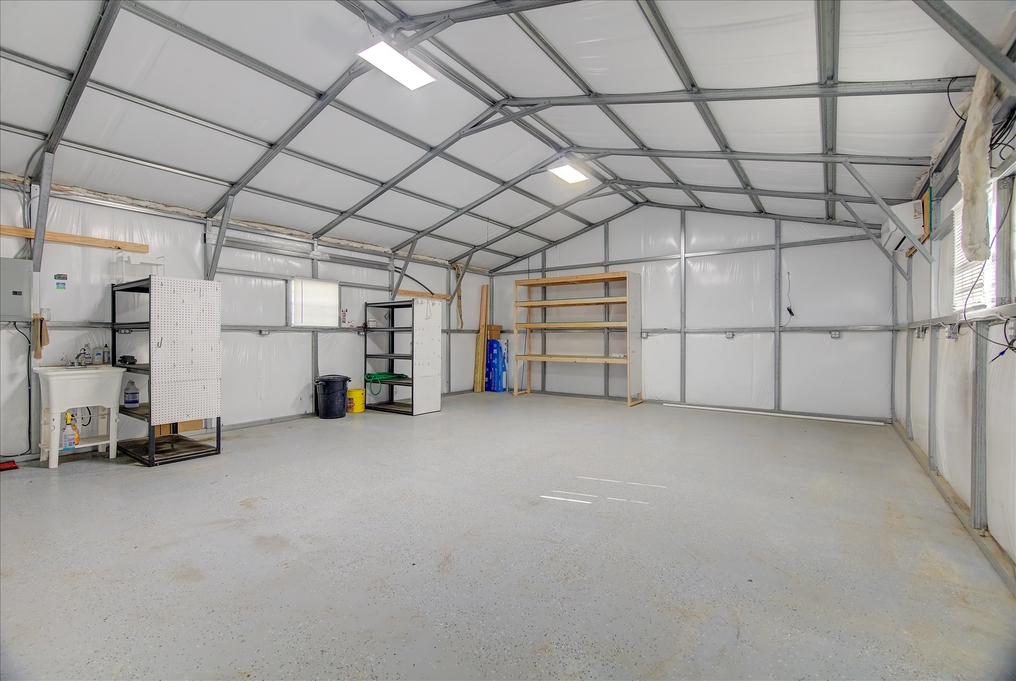 16738 Rockwall Street Conroe, TX 77303 - Photo 37 of 42 Well-maintained insulated workshop with bright overhead lighting, durable flooring, built-in shelving, and a utility sink. Ideal for hobbies, storage, or workspace needs, with ample room for equipment and organization.