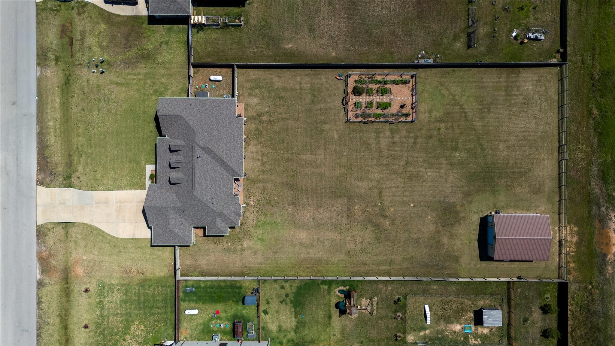 16738 Rockwall Street Conroe, TX 77303 - Photo 41 of 42 Overhead aerial view showcasing the full fenced homesite, highlighting the home’s footprint, expansive backyard, dedicated garden area, and separate workshop/outbuilding. The layout clearly demonstrates the usable space, privacy, and flexibility for outdoor living, hobbies, or future additions.