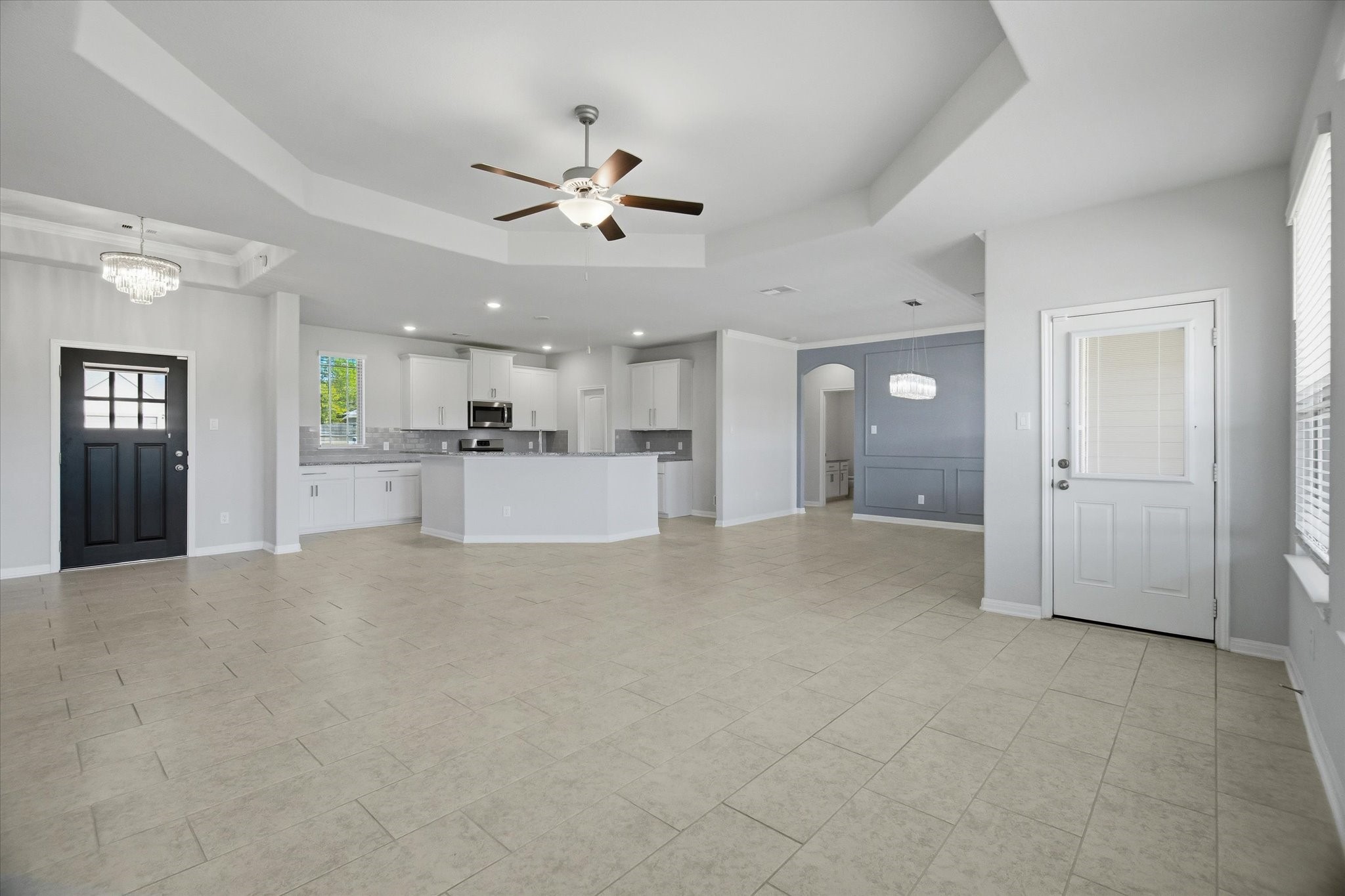 16738 Rockwall Street Conroe, TX 77303 - Photo 7 of 42 The family room opens up to an expansive yet comfortable space, designed for both everyday living and lively gatherings. Oversized tile flooring runs through the main living areas and is paired with substantial baseboards. The crisp, neutral color palette enhances the home’s clean, modern feel.