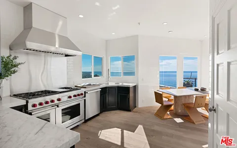 a kitchen with stainless steel appliances kitchen island granite countertop a sink dishwasher a stove and a refrigerator with wooden floor
