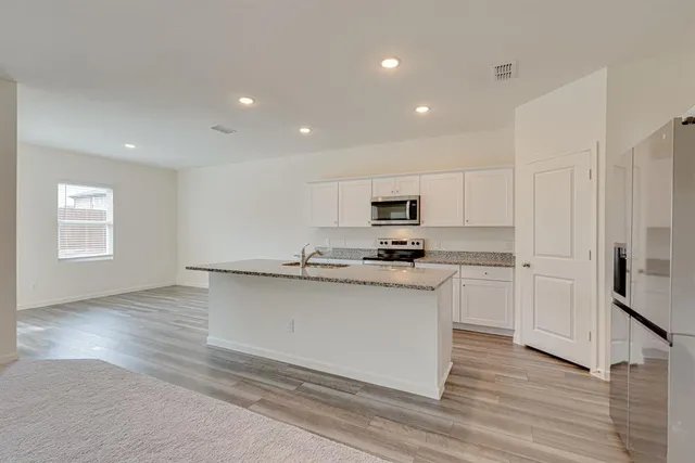 a kitchen with stainless steel appliances a sink a stove a refrigerator and cabinets