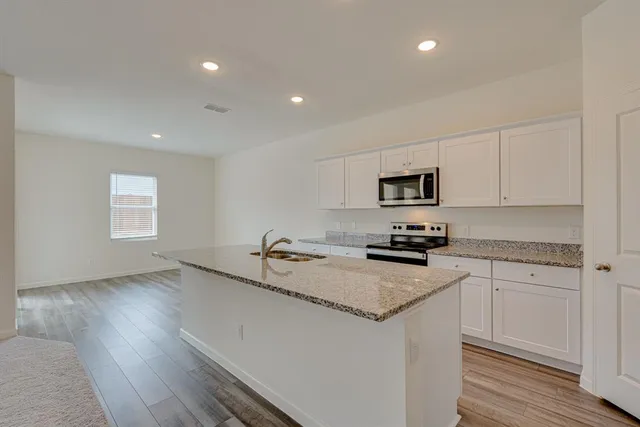 a kitchen with granite countertop a sink stainless steel appliances and white cabinets