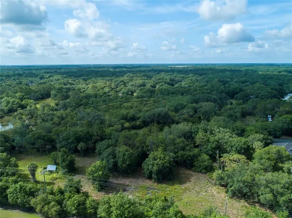 an aerial view of a field with houses in back