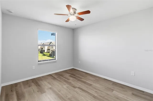 an empty room with wooden floor fan and windows