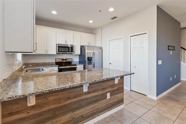 a kitchen with granite countertop a sink stainless steel appliances and cabinets