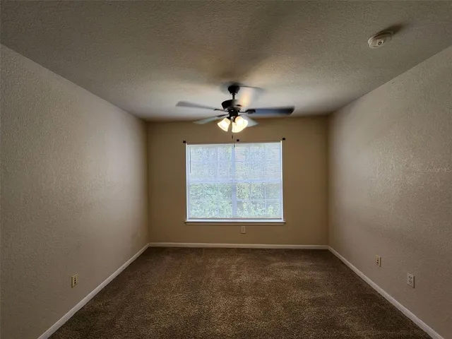 an empty room with a window and a fan