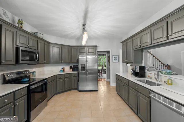 a kitchen with stainless steel appliances granite countertop a sink a stove top oven a refrigerator cabinets and a window